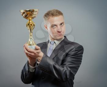 portrait of gesturing pride businessman with gold cup. Concept of win and success