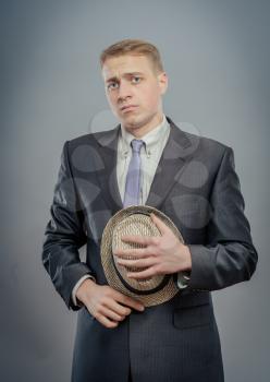 Young man in suit is holding a straw hat