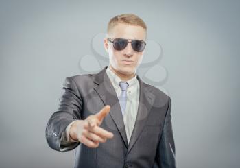 You are the next! Confident young businessmen in sunglasses standing isolated on grey and pointing on camera