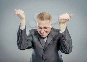 Closeup portrait happy successful business man winning, fists pumped celebrating success isolated grey wall background. Positive human emotion, facial expression. Life perception, achievement