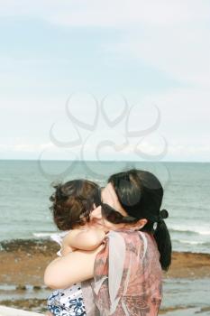 Mother hugging her baby over sea 
