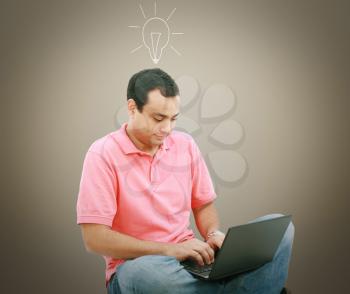 Man using a laptop with light bulb over his head 
