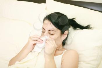 Closeup of gorgeous caucasian woman with cold sneezing into tissue over white background 
