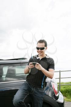 Happy man using his mobile outside his car
