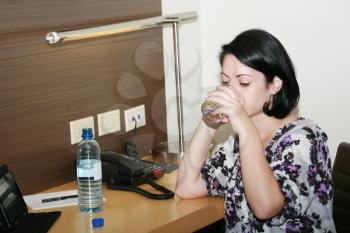 Portrait of beautiful business woman drinking water at office 