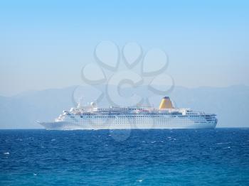 Big cruise vessel side view with water surface in front and mainland in back.