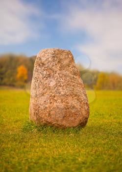 Big granite rock lying on a green grass