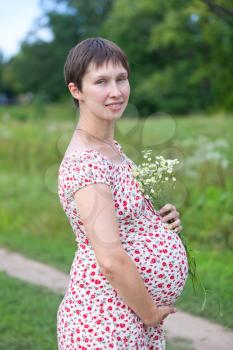 Pregnant woman with chamomile bouquet on green background
