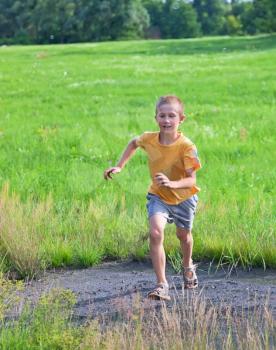 Small boy running on green meadow, summertime
