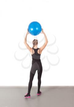 Athletic young woman with blue ball in the gym
