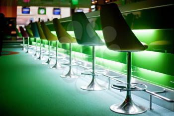 Chairs in row in bar with green lights