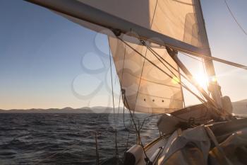 Sailboat crop during the regatta at sunset ocean
