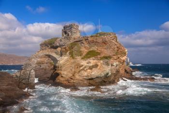 Rock and lighthouse at the stormy sea on greek island Andros
