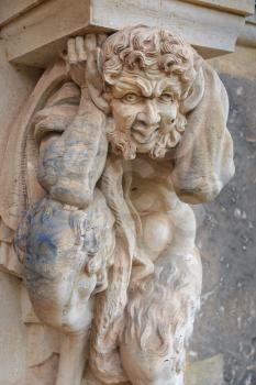 Closeup half naked faunus statue under column at Zwinger palace in Dresden, Germany
