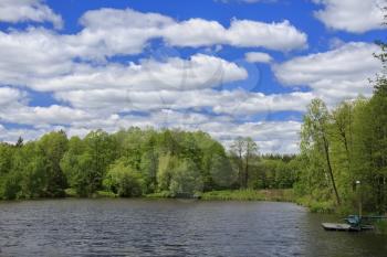 Blue sky with clouds, lake and forest at sunny day
