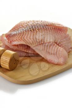 tilapia fillets on a cutting board with spices