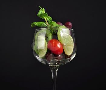 assortment of fresh fruits in a wineglass on black background