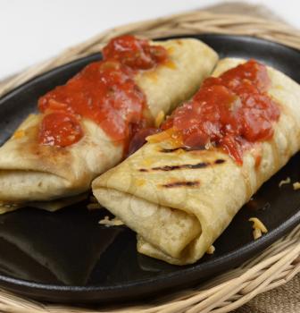 Two Mexican Burritos With Cheese And Salsa