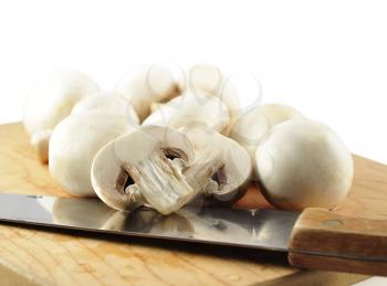 white mushrooms with knife on a cutting board