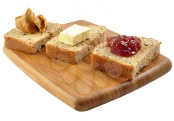 bread with jelly , peanut butter and butter on a cutting board