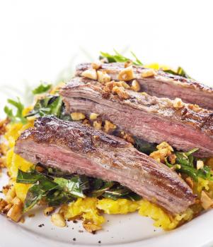 flank steak with mashed plantain , collard greens and ginger peanuts , close up