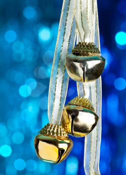 Christmas bells with ribbon, defocused blue lights on background 
