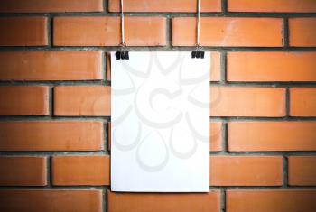 Blank white poster on a rope, brick wall on the background