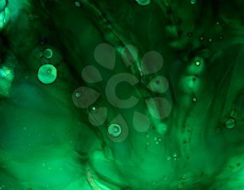 Deep green cloudy texture with splatters.Colorful background hand drawn with bright inks and watercolor paints. Color splashes and splatters create uneven artistic modern design.