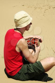 Royalty Free Photo of a Boy Playing a Drum in the Desert