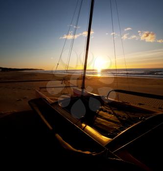 Royalty Free Photo of a Catamaran on a Beach at Sunset