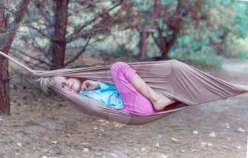Happy Child girl in hammock in summer forest