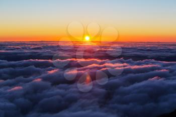 Beautiful sunset on the hill above clouds