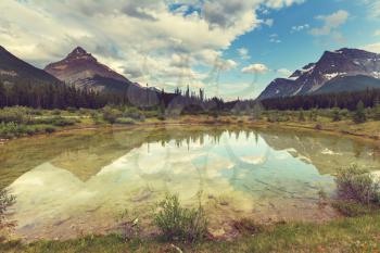 Serene scene by the mountain lake in Canada with reflection of the rocks in the calm water.