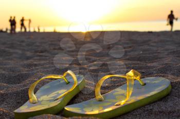 Sandals on sand with beautiful sunset