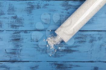 Bath salt in bottle on blue wooden background