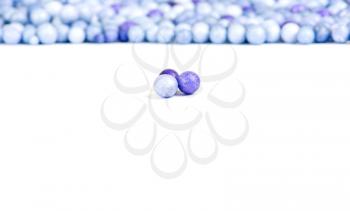 One blue and two violet little pearls isolated on background of other pearls.