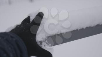 Man in black gloves touches, an icy railing, on a winter street.