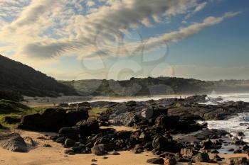 Picture of White Clouds and Blue Skies with Black Rocks and Beach