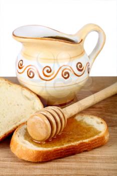 honey in a jug and loaf on board isolated on white background