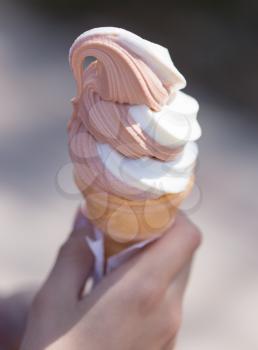 Ice cream in a waffle cup in a hand .