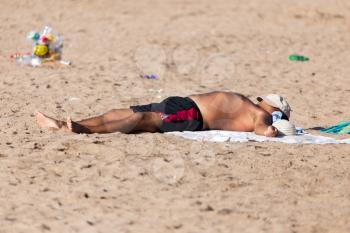 man sunbathes on the dirty beach