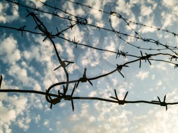 Barbed wire against the sky with clouds .