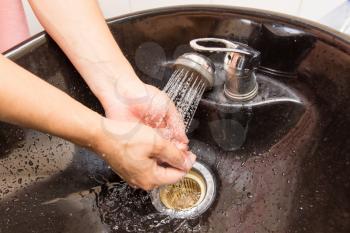 The man washes his hands in the sink .