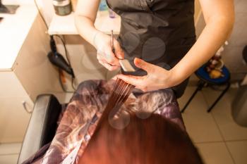 Female haircut with scissors in the beauty salon .