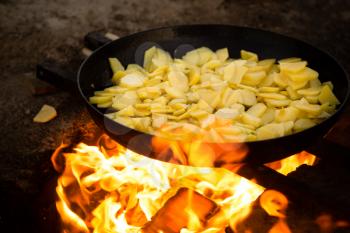 Potatoes fried in a frying pan in the open air .