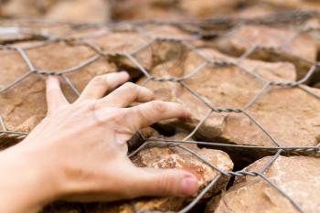 Man's hand on a stone wall in nature