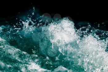Splash of stormy water in the ocean on a black background .