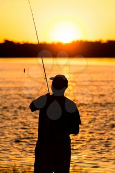 Fisherman with a fishing rod at sunset .