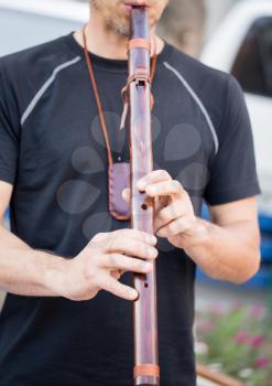 the man is playing on a wooden pipe .