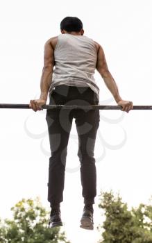 the man pulls himself up on the bar .